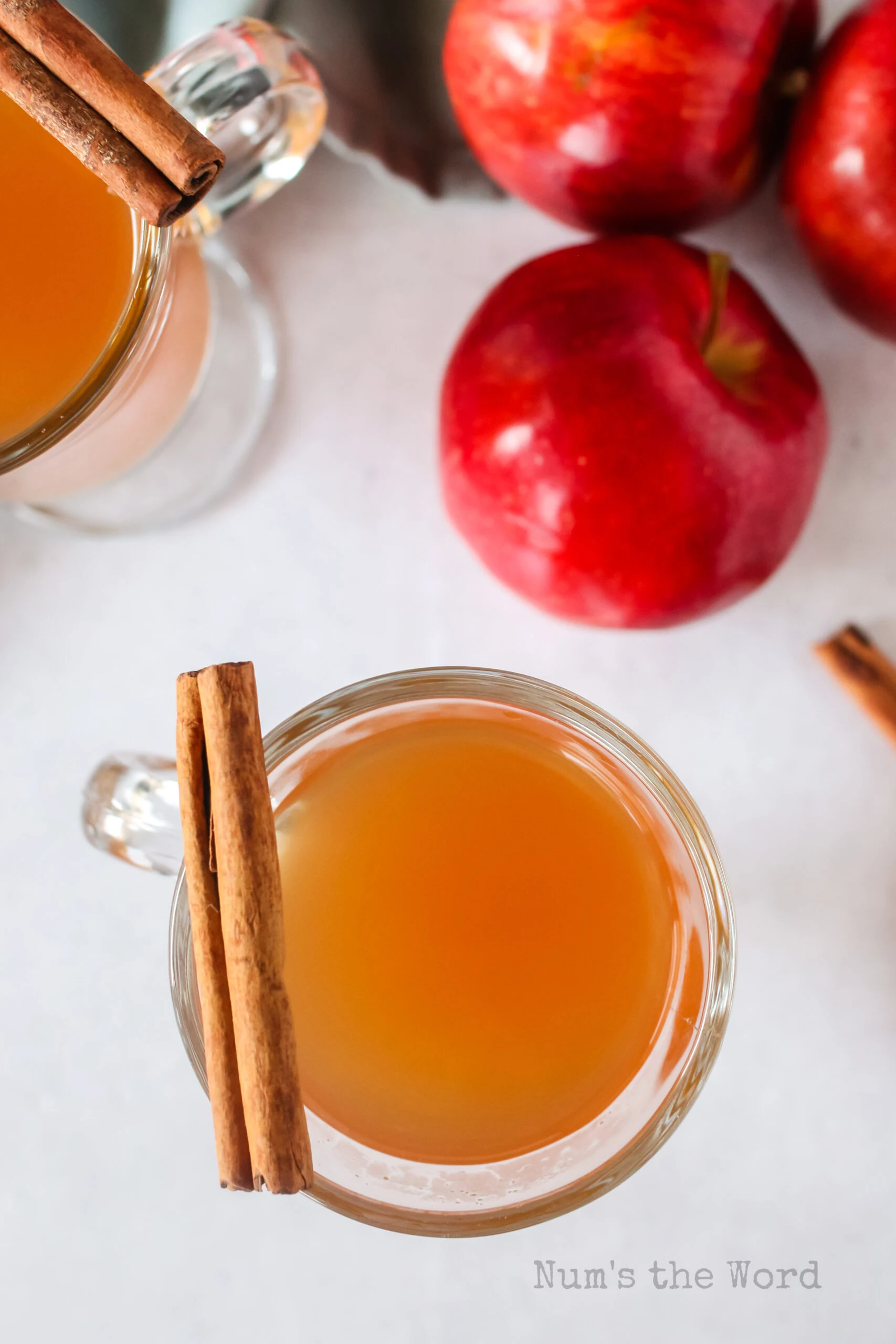 Top view looking down at two glasses of apple cider with cinnamon sticks.