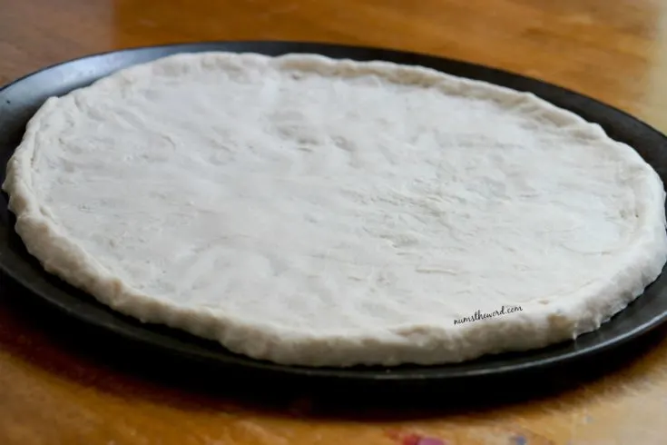 30 Minute Pizza Dough - side view of pizza dough spread out on pan, side view