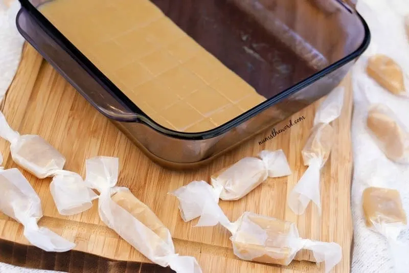 Microwave Caramels - pan of caramels on cutting board with wrapped caramels all around.