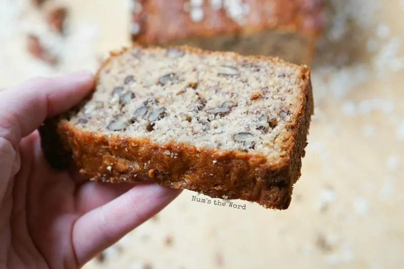 Oatmeal Pecan Banana Bread - hand holding a slice of bread to show details of what inside looks like.