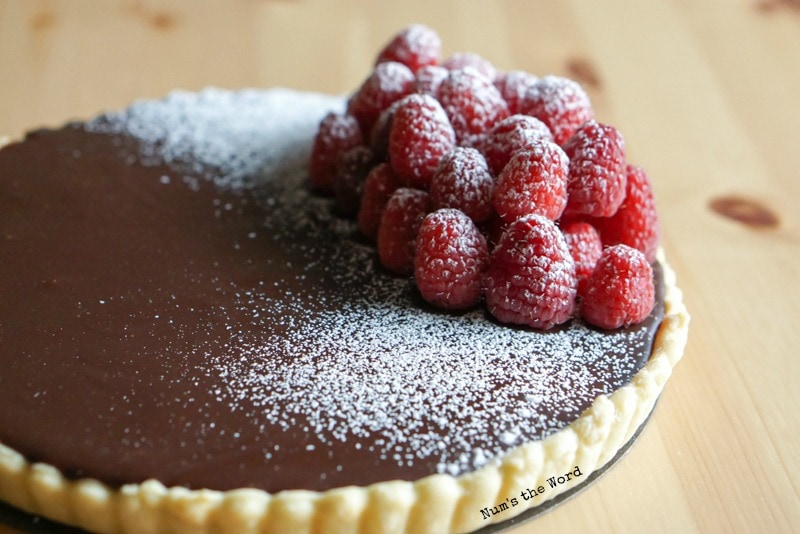 Raspberry Chocolate Tart - side view of tart and raspberries pied on high uncut