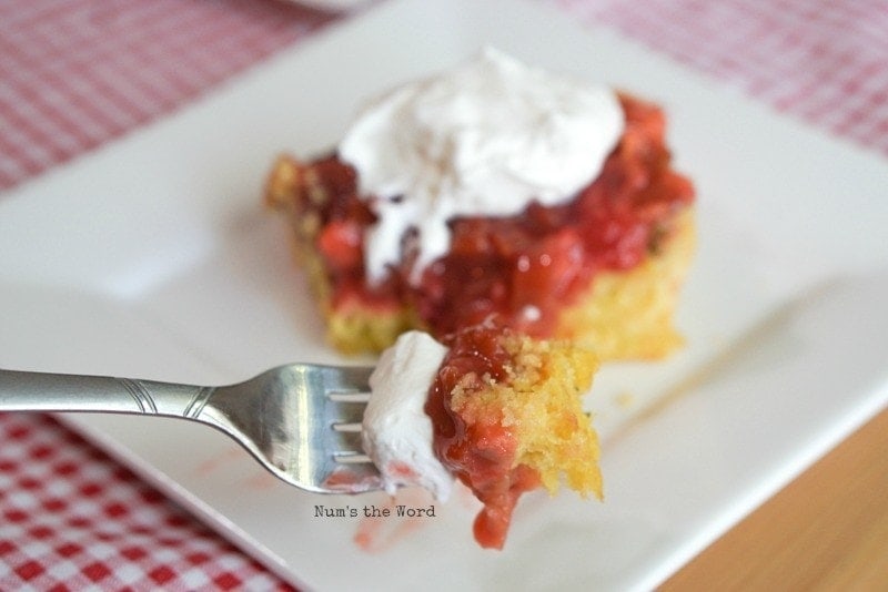 Serving slice of Strawberry Rhubarb Lemon Upside Down Cake topped with whipped cream