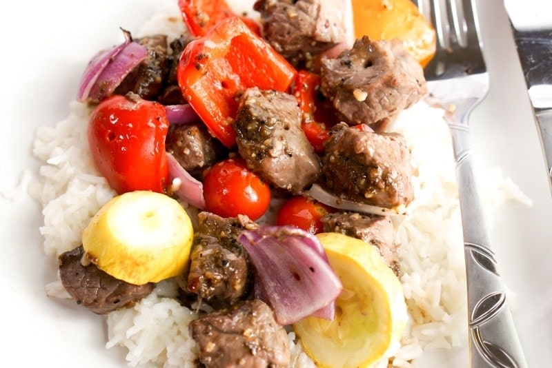 Close up photo of marinated steak kabobs over rice