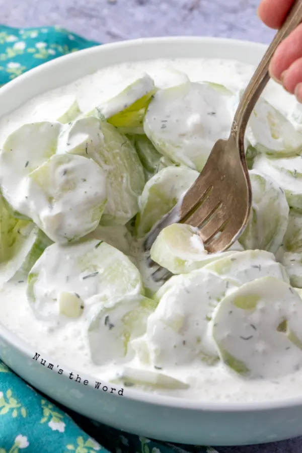 cucumber salad in serving bowl with fork about to pick one up