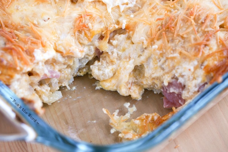 Schinken-Tater-Tot-Frühstücksauflauf - gebackener Auflauf in der Pfanne mit einer herausgenommenen Scheibe