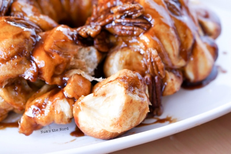 Caramel Pecan Monkey Bread - close up of monkey bread with piece pulled off and sitting in front.