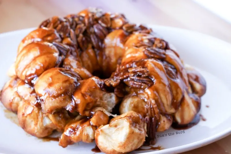 Caramel Pecan Monkey Bread - zoomed out photo of monkey bread with piece pulled off and sitting in front.