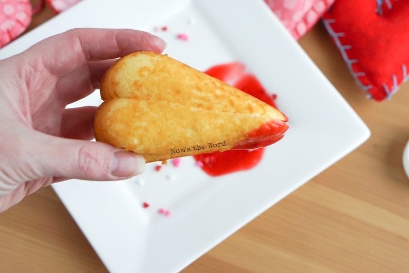 Twinkie Hearts - Hand holding twinkie heart on its side, already dipped in raspberry puree.