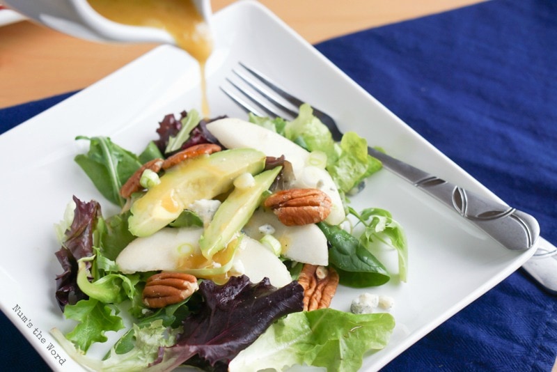 Roquefort Pear Salad - Salad on plate with dressing being drizzled on top