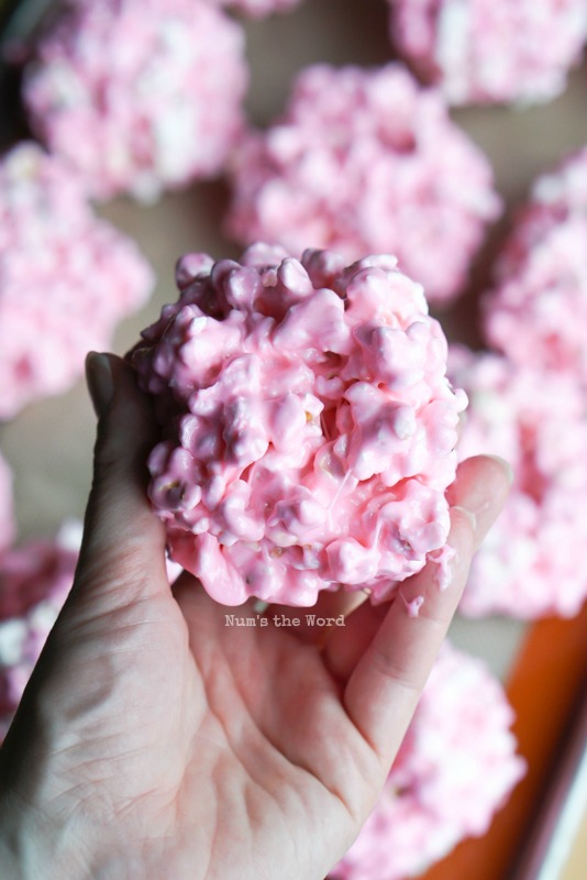 Hand holding up a peeps popcorn ball.