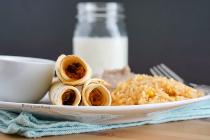 Pulled Pork Flautas - front view of baked flautas on a plate with all the fixings