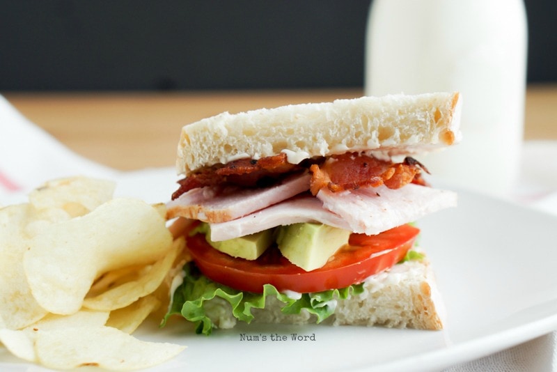 Roasted Turkey & Avocado BLT = close up of sandwich on plate with chips