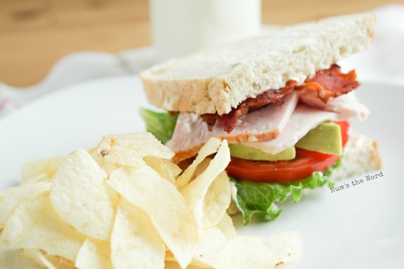 Roasted Turkey & Avocado BLT - side angle of sandwich on plate with potato chips