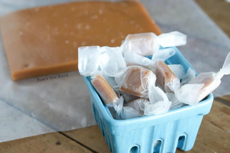 Sea Salt Caramels - rolled caramels in a blue dish ready to be eaten. Caramel slab in background waiting to be cut