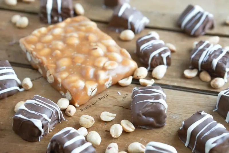 Salted Peanut Caramels - Caramels drizzled with white chocolate with a small slab of plain peanut caramels next to the finished ones.