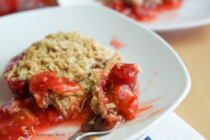 Cherry Rhubarb Crisp - two plates of crisp and pan of crisp in background. Fork full of crisp ready to be eaten.