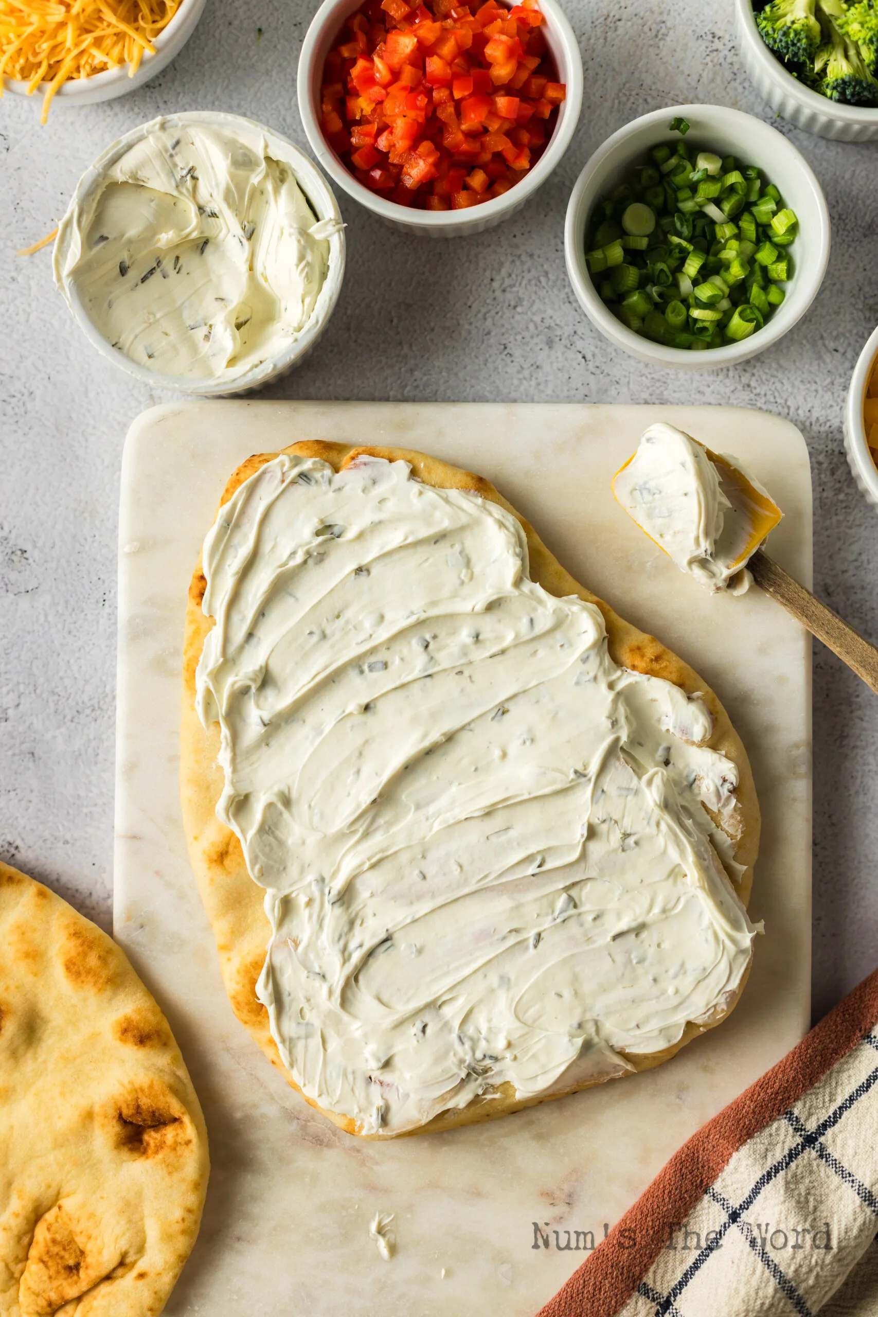 cream cheese spread out over a piece of naan bread