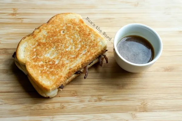 Leftover Pot Roast Grilled Cheese - cooked sandwich on cutting board, uncut with au jus