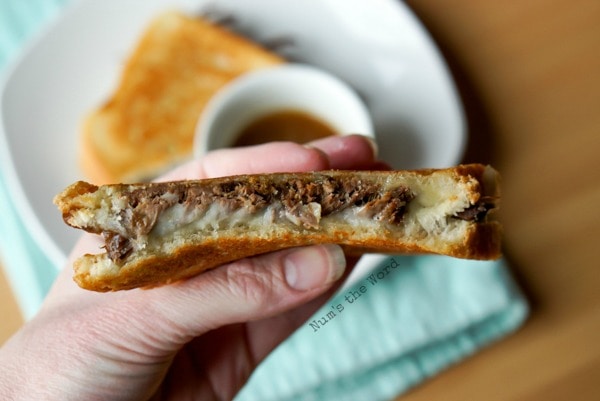 Leftover Pot Roast Grilled Cheese - hand holding sandwich to show meat and cheese filling.