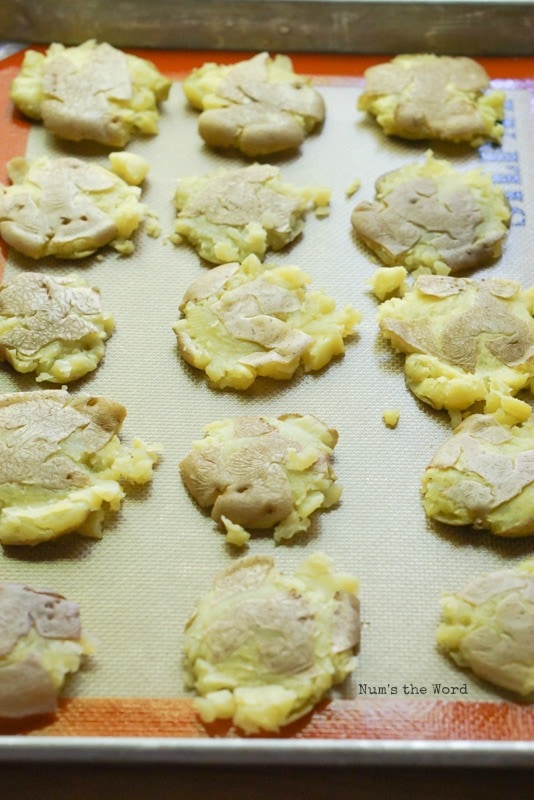 Loaded Smashed Potatoes - 15 smashed potatoes lined up on a baking tray