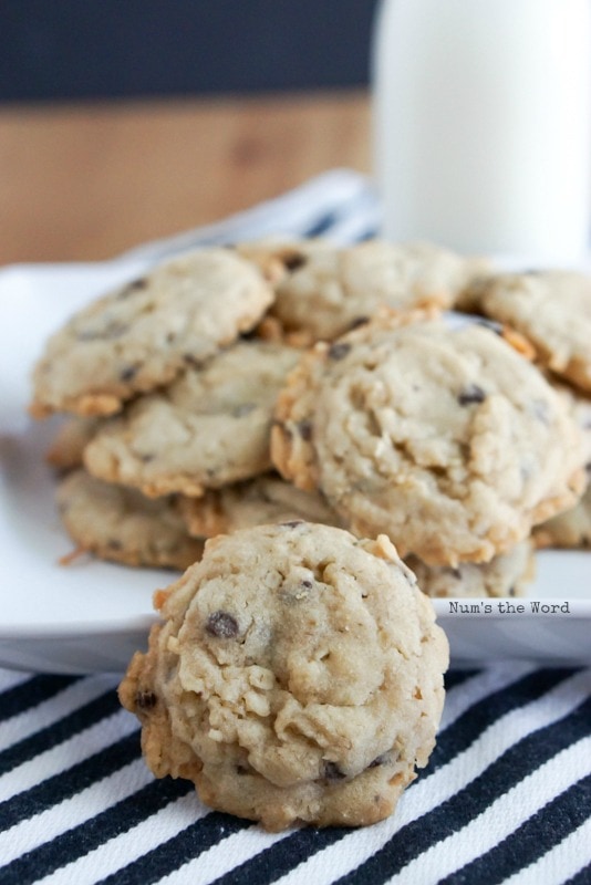 Krispy Coconut Oatmeal Cookies - cookies piled high on plate with one up front to show details with glass of milk in background