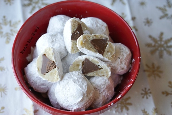 Surprise Snowball Cookies - cookies cut in half on top of uncut cookies to show off chocolate center