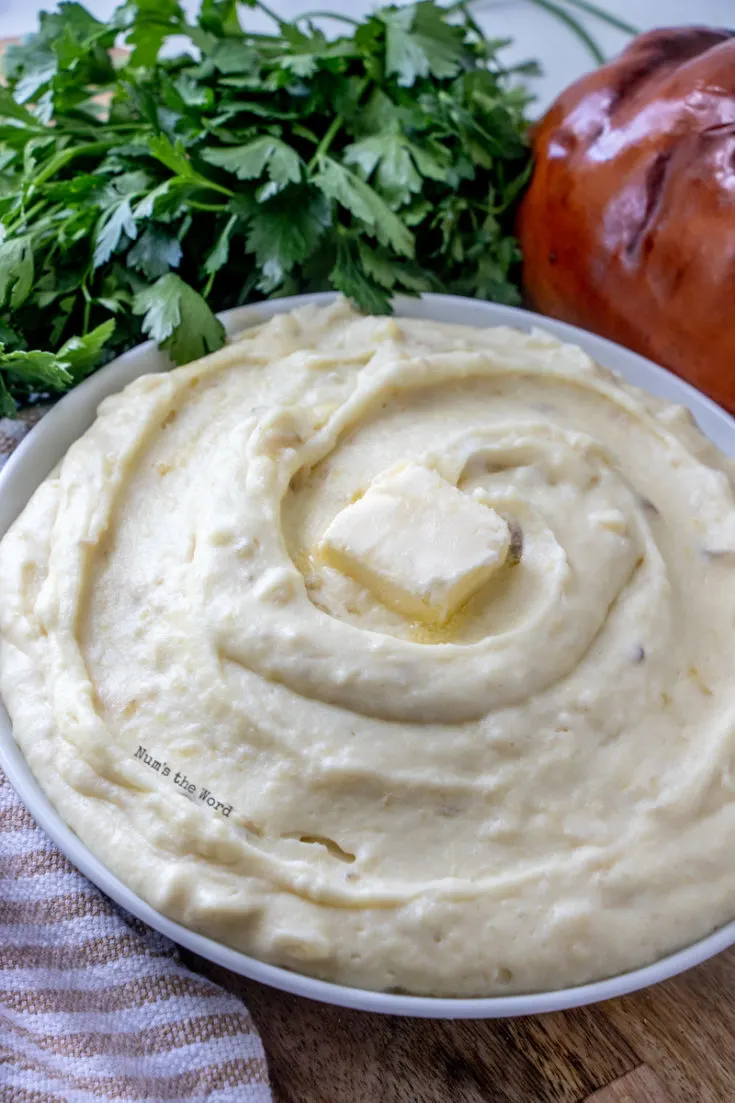 Mashed Potatoes with Sour Cream - potatoes in a serving bowl with pat of butter on top