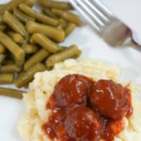 Chili Cranberry Meatballs - meatballs over mashed potatoes on plate with green beans