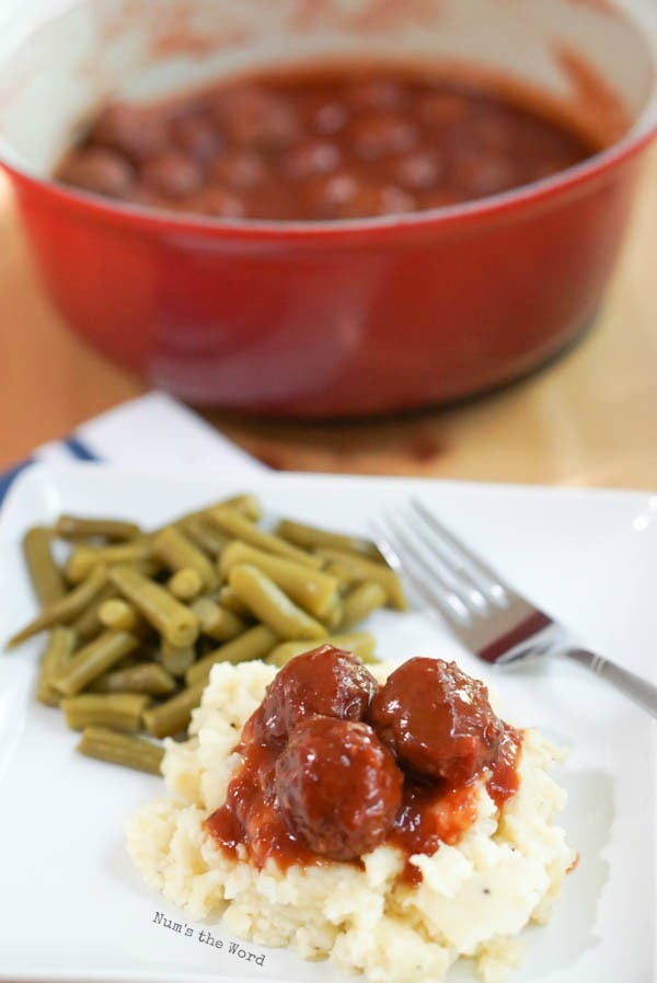 Chili Cranberry Meatballs - meatballs on plate over mashed potatoes, with pot full of meatballs in background