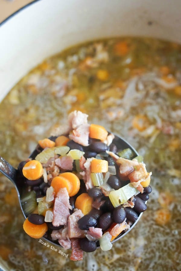 Ham Bone & Vegetable Soup - ladle of soup mixture held above pot of soup