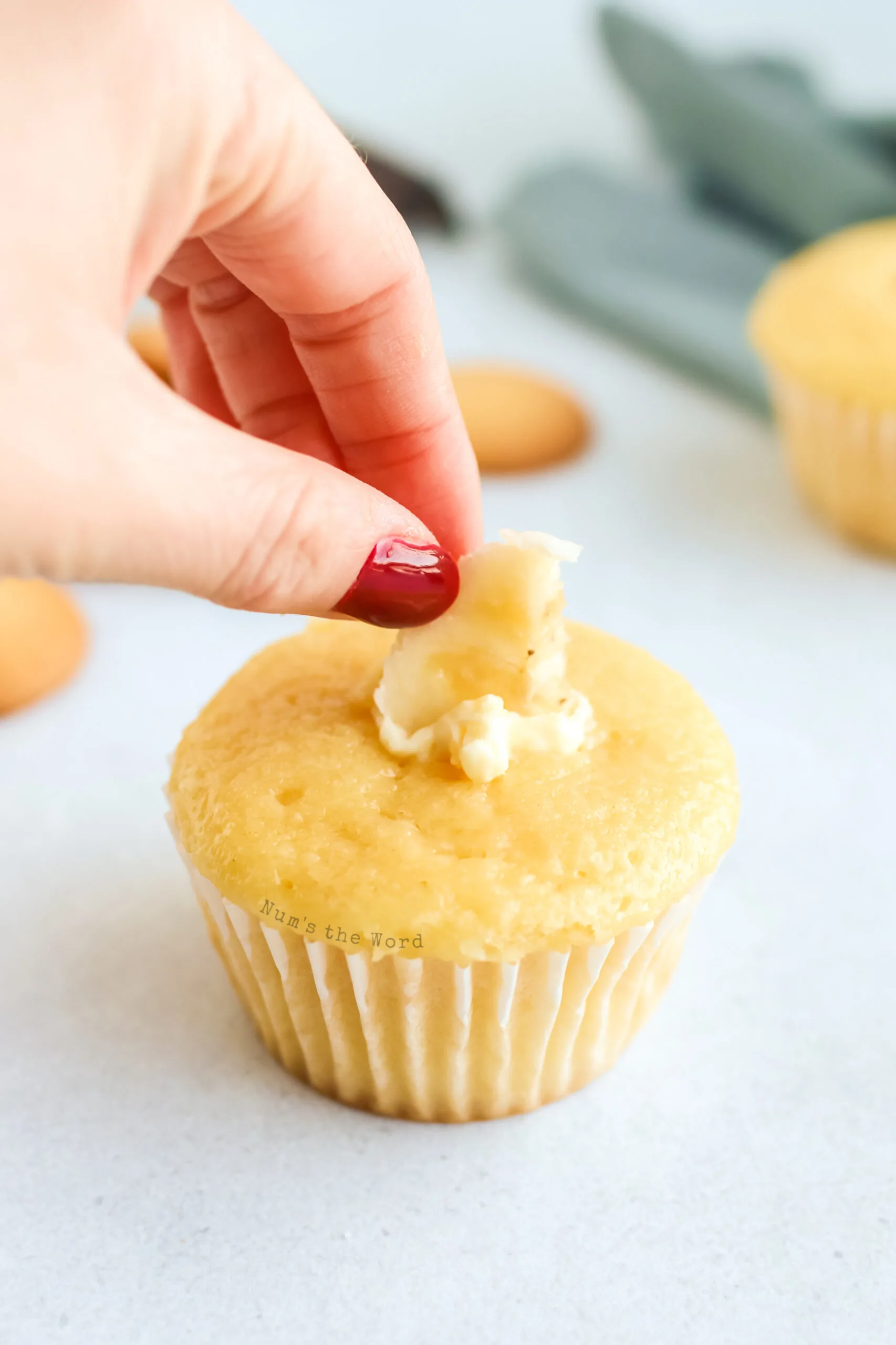 banana slice being pushed into the middle of the cupcake.