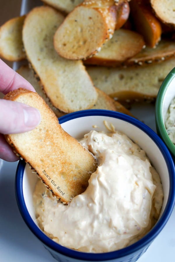 Bagel Chips - hand holding a bagel chip and dipping into a bowl of dip