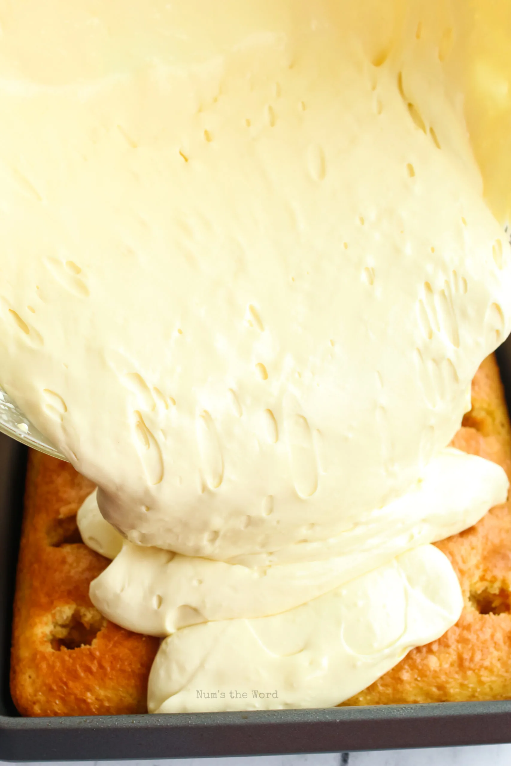 banana pudding being poured over poke cake