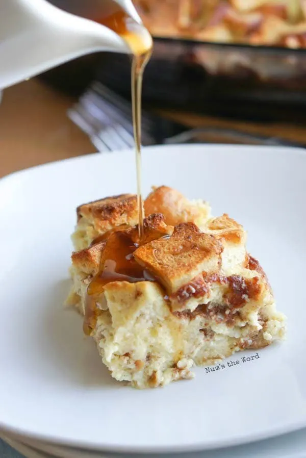 Bagel French Toast Casserole - slice of casserole on plate with maple syrup being drizzled over.