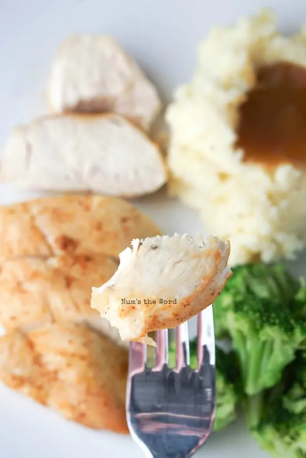 Air Fryer Chicken Breasts - fork holding up a piece to show the camera how tender it is.