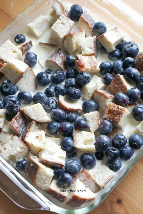 Blueberries placed on top of bread pudding before baking