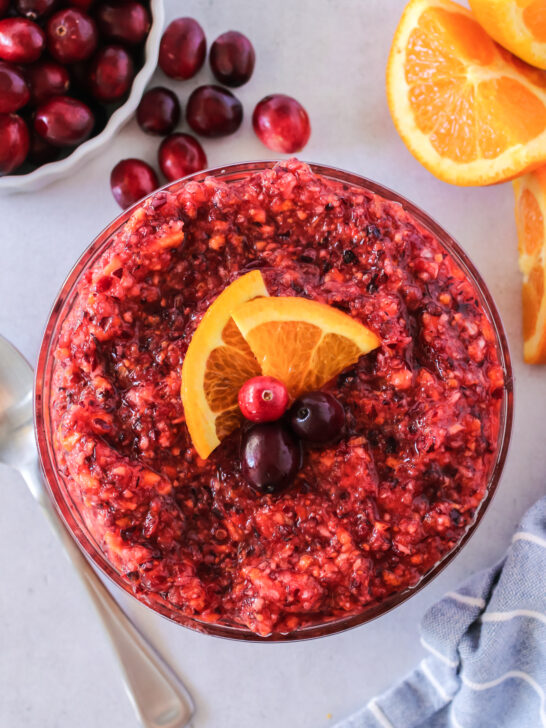 Cranberry Orange Relish in a serving bowl topped with orange slices and whole cranberries.