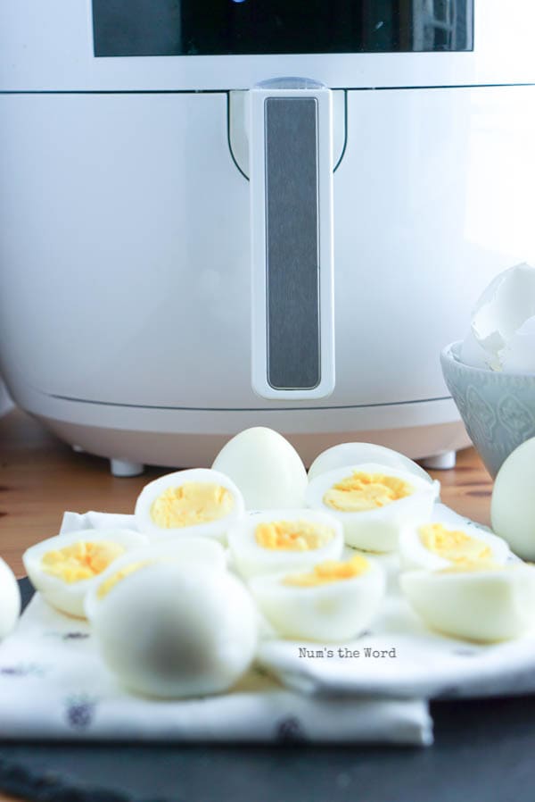 Air Fryer Hard Boiled Eggs - eggs sliced in half with air fryer in background