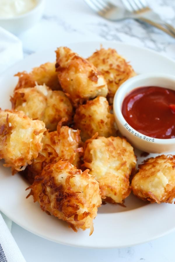 Gluten Free Coconut Chicken - close up of chicken nuggets on plate with sauce