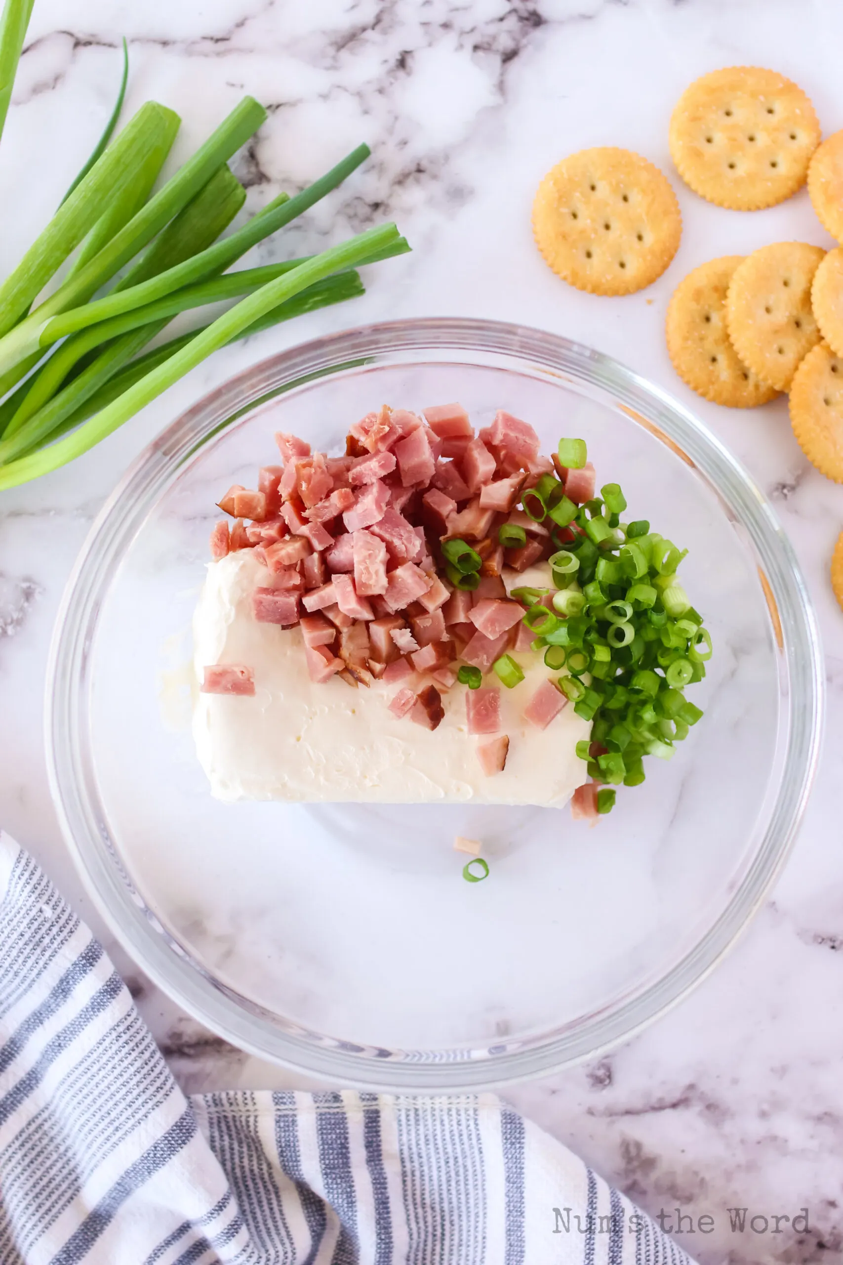 cream cheese, ham and green onions in a bowl, unmixed.