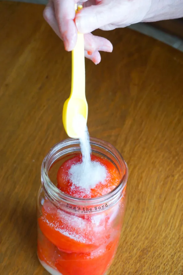 canning and pickling salt being added to tomatoes