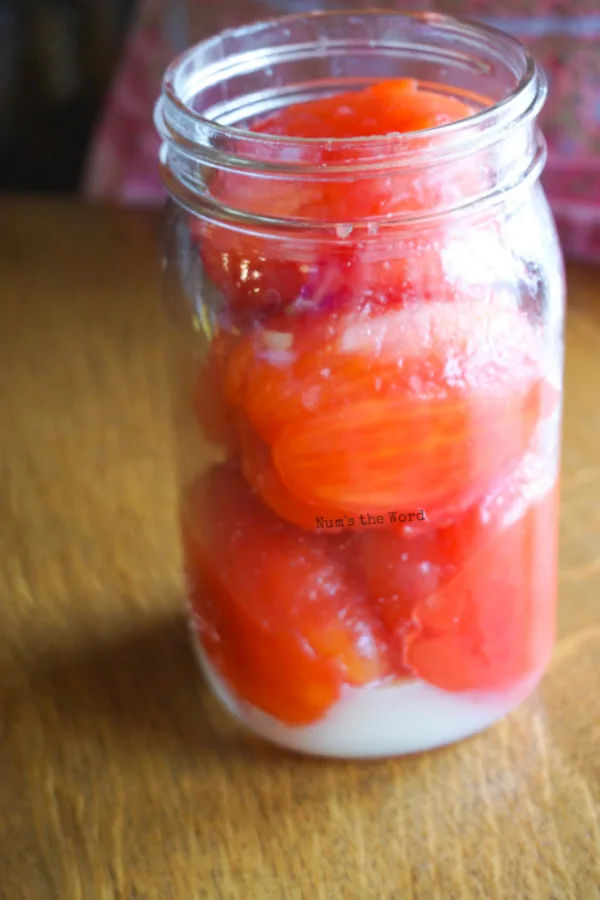 whole tomatoes in a jar with lemon juice