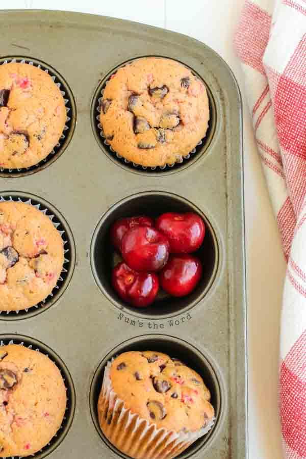Banana Chocolate Chip Muffins - muffins in tin with one muffin missing and cherries in the missing hole.