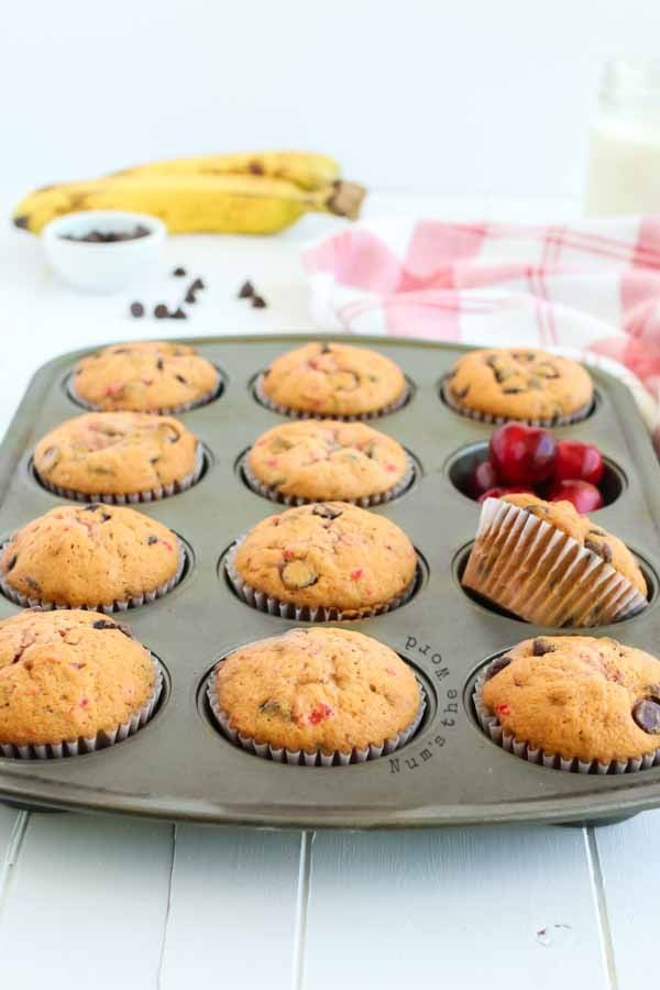 Banana Chocolate Chip Muffins - full muffin tin of baked muffins with cherries 