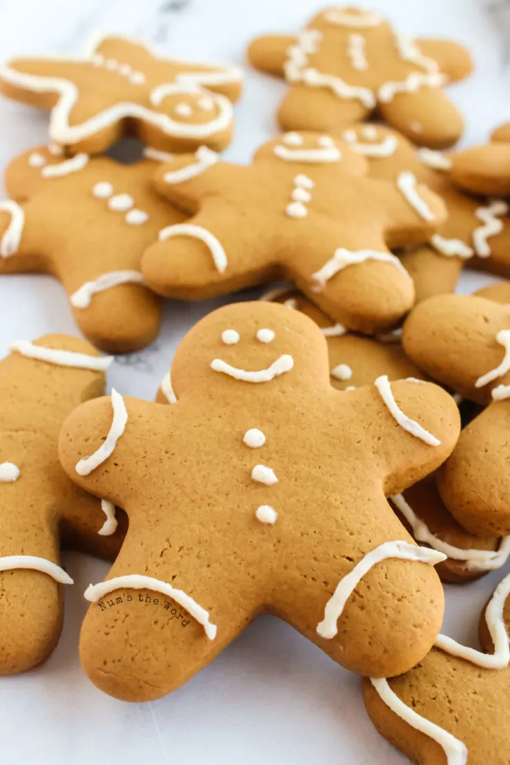 zoomed in image of decorated gingerbread cookies on parchment paper stacked on top of each other