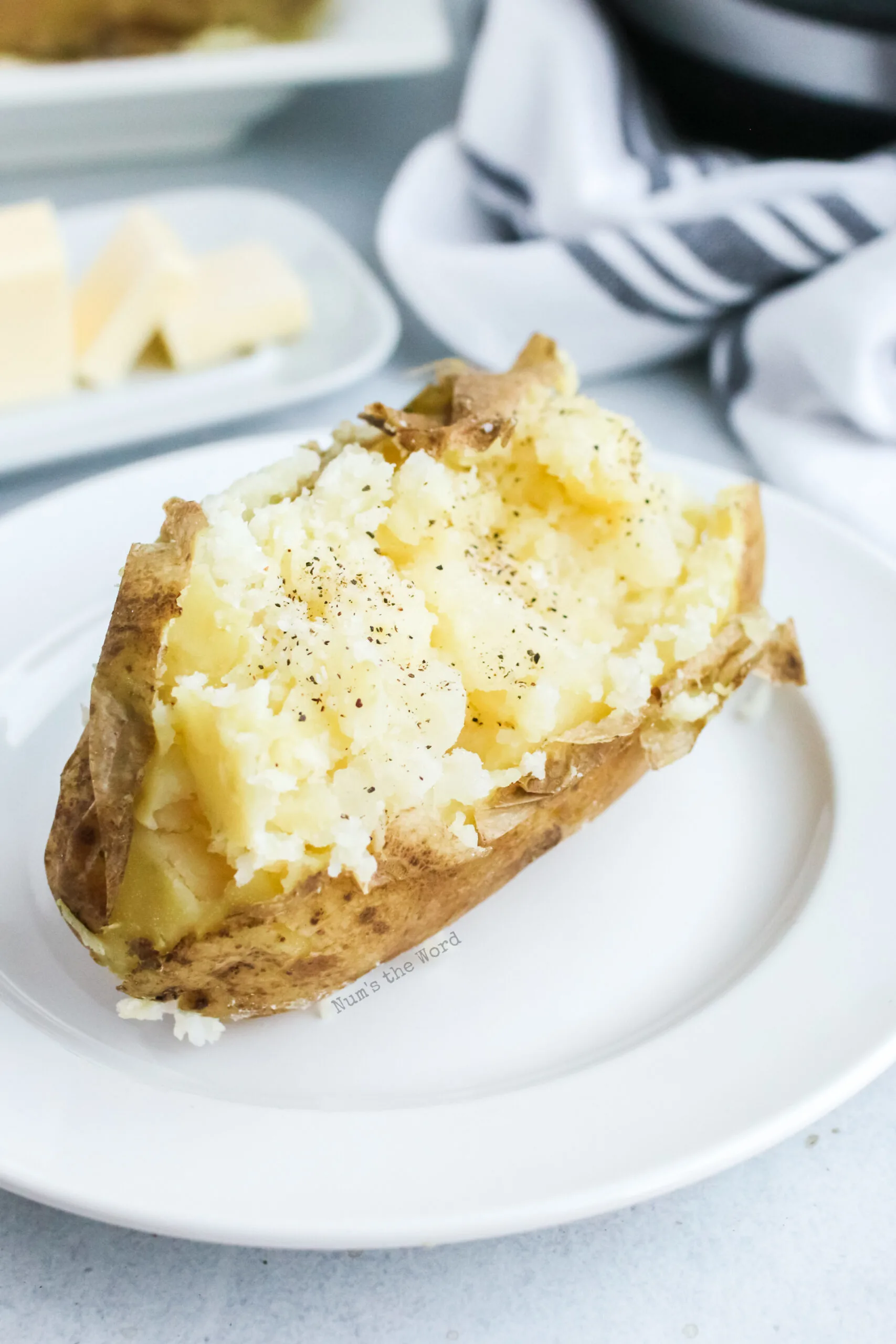 Single baked potato on a plate with salt and pepper