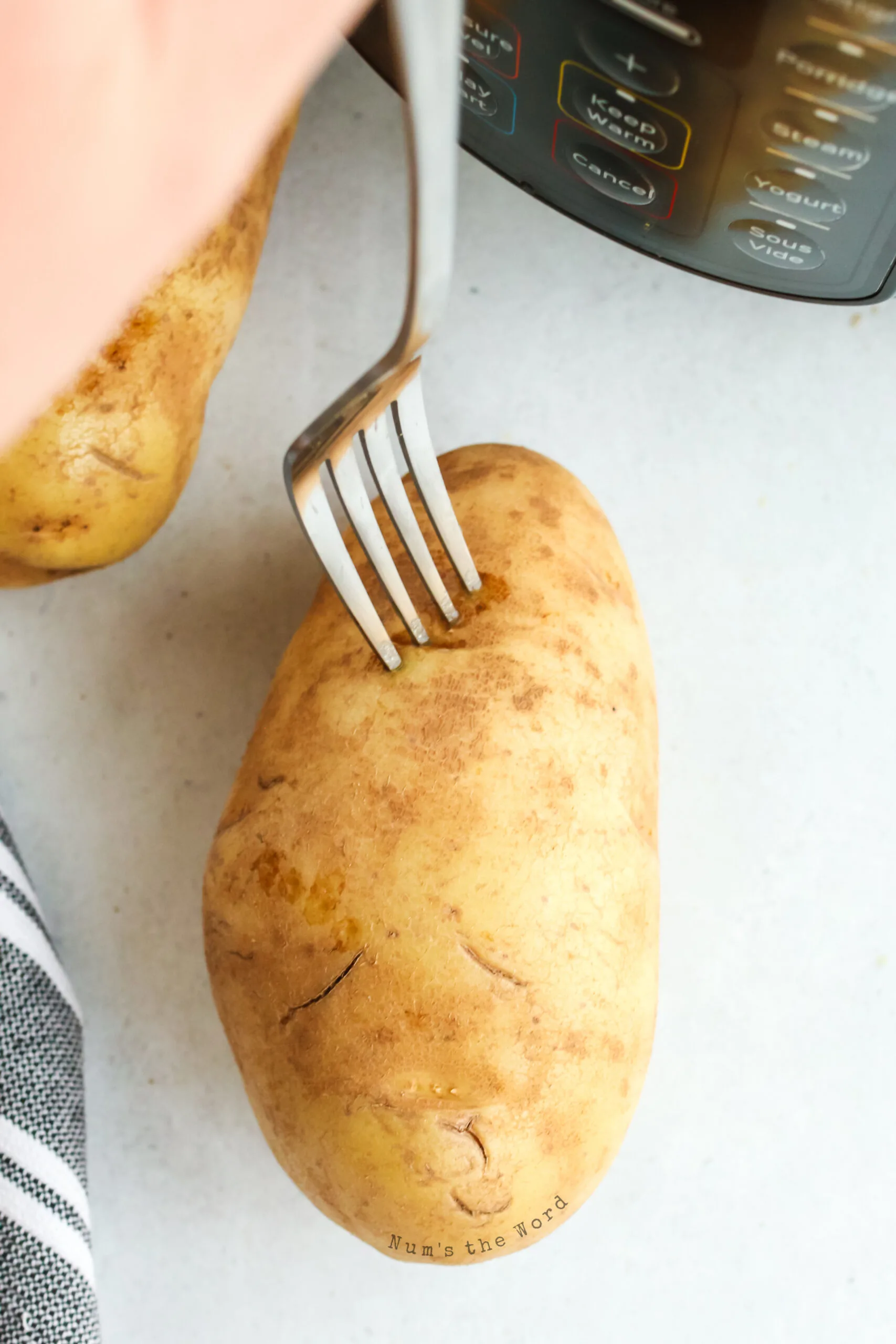 fork pricking a washed and uncooked potato