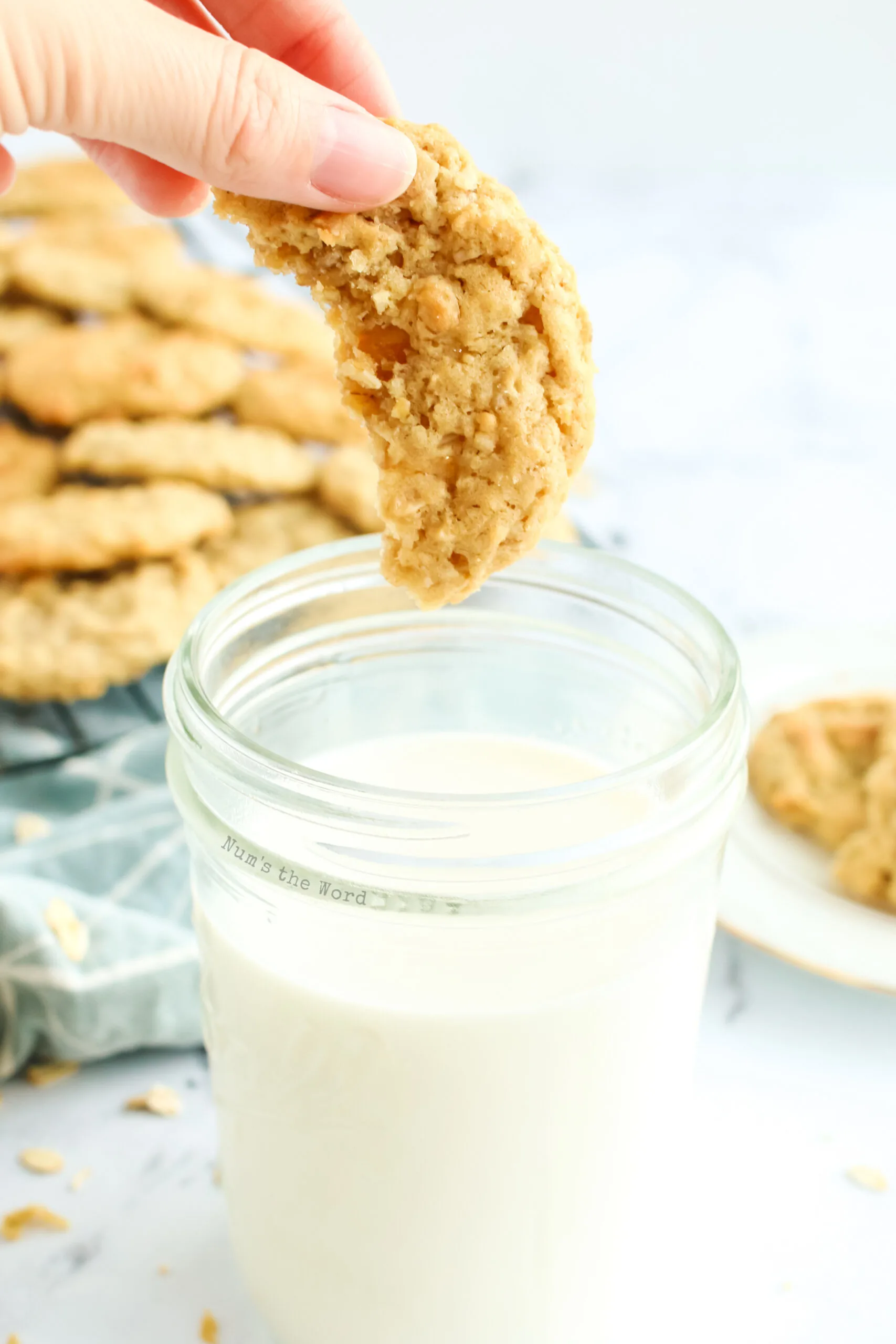 hand dipping cookie into a glass of milk