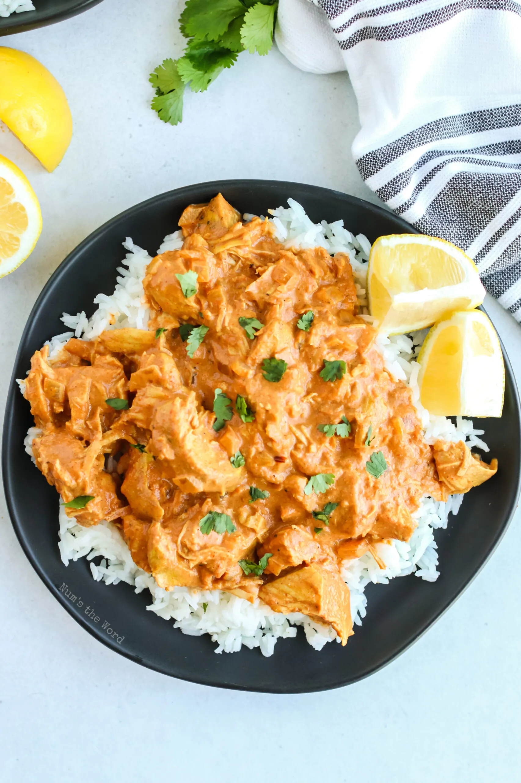 plate full of rice and tikka masala with lemon wedges on plate