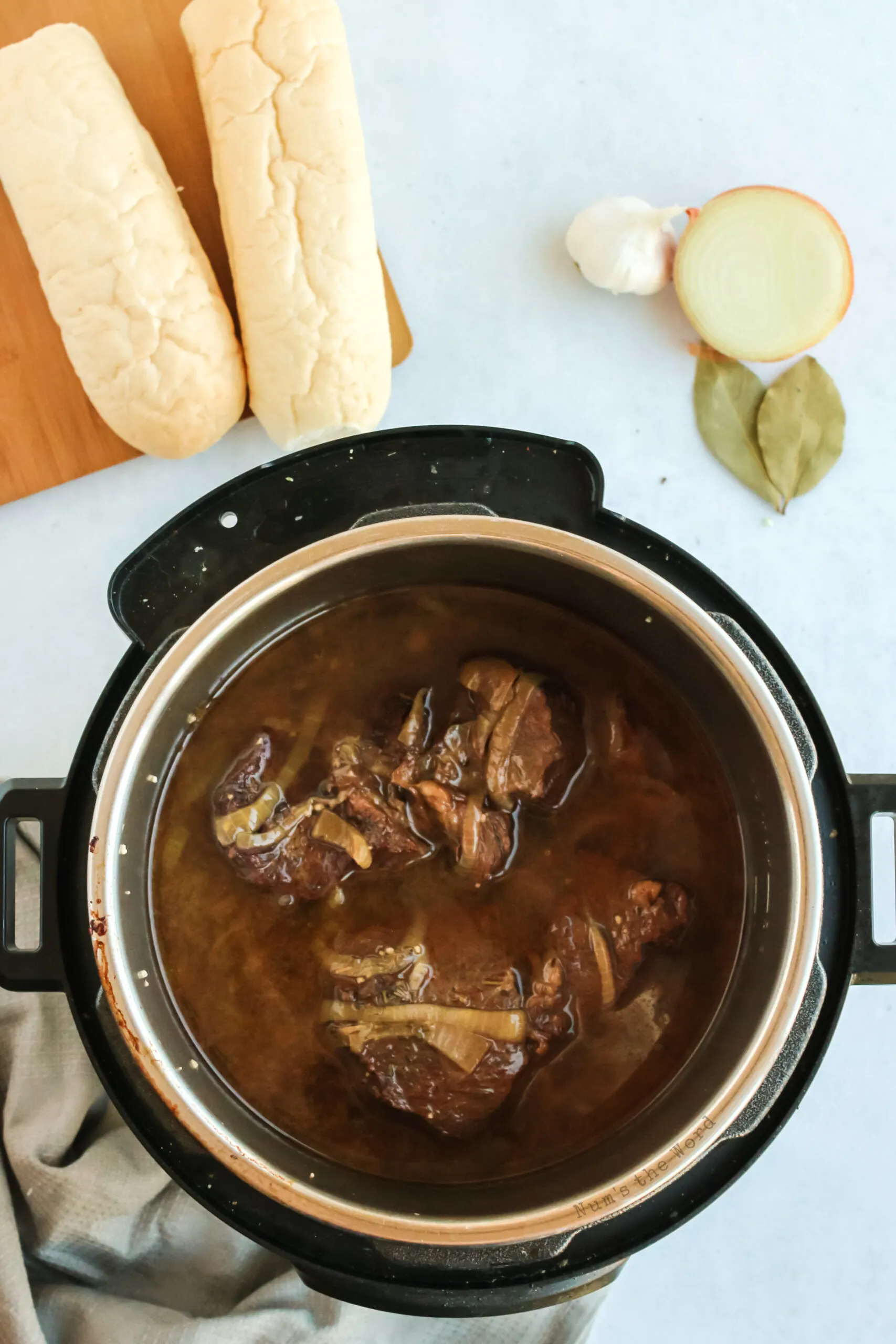 cooked beef and onions in instant pot, ready to be shredded.